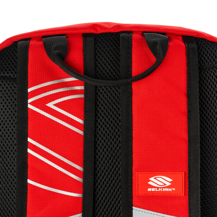 Red backpack shoulder straps with black mesh padding and a small patch reading SELKIRK.