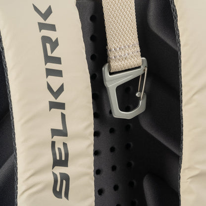 Vertical SELKIRK logo on beige backpack back panel, perforated black foam and metal strap clip.