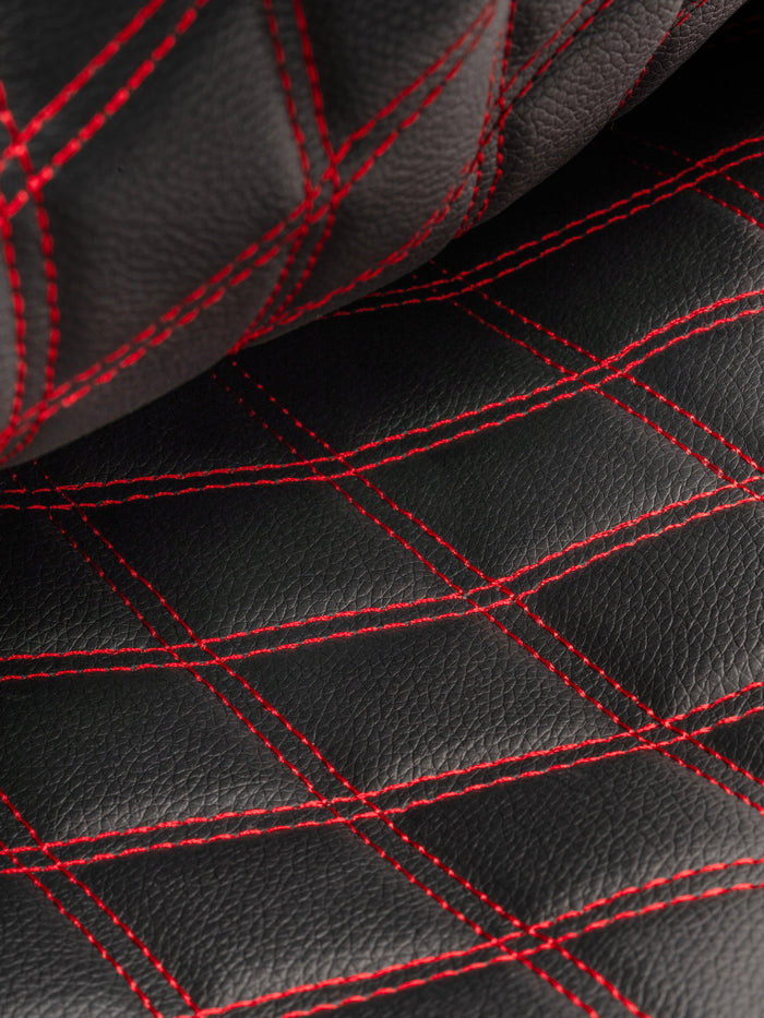 Close-up of black leather with red diamond-quilt stitching