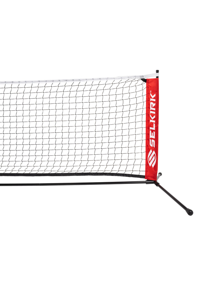 Pickleball net panel with red sleeve labeled SELKIRK and black mesh net on tripod base