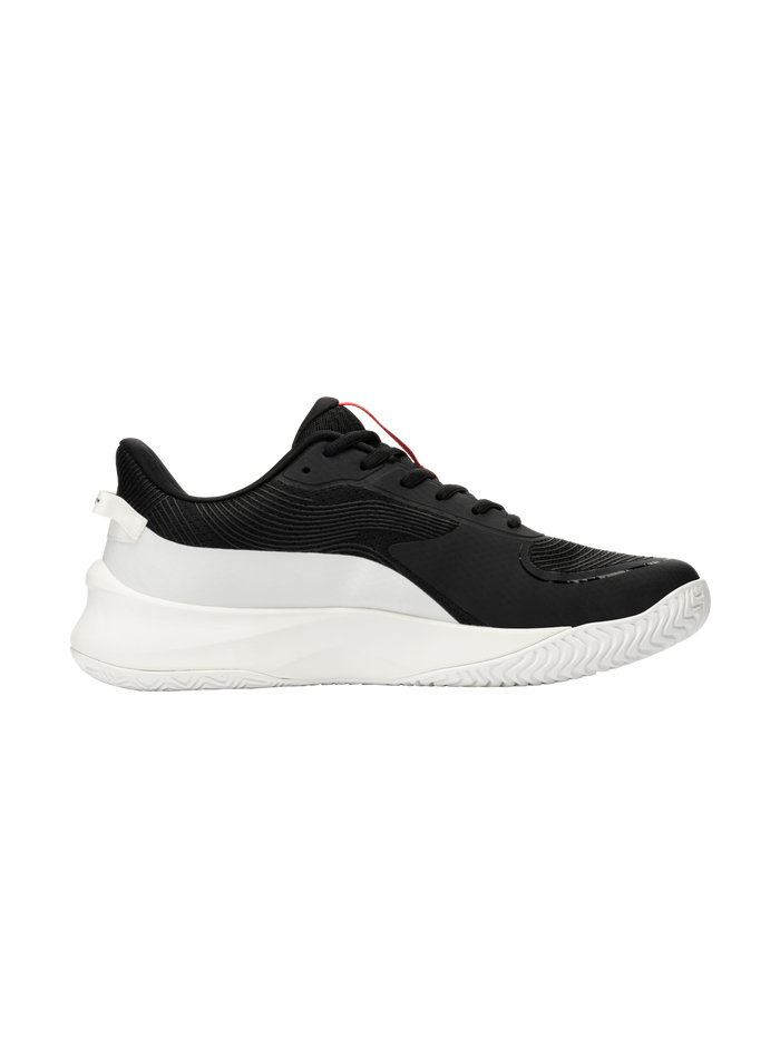 Black low-top athletic sneaker, side view; textured upper, white chunky sole, red tongue pull tab.