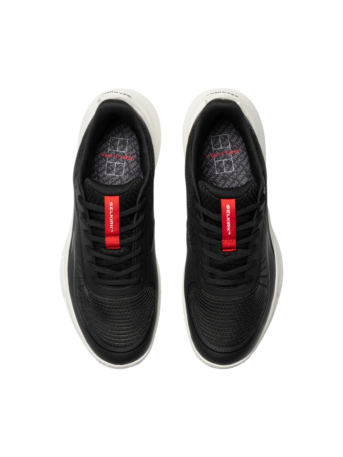 Top view of black athletic sneakers with red tongue labels reading 'Selkirk' and white midsoles.