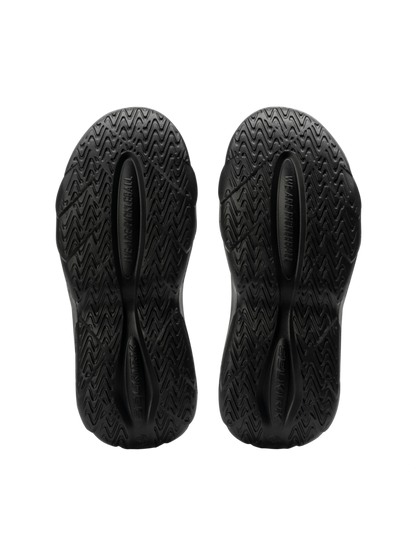 Bottom view of Selkirk Renew Pickleball Recovery Shoe showing black molded EVA outsoles with textured tread and ‘WE ARE HUMAN’ imprint
