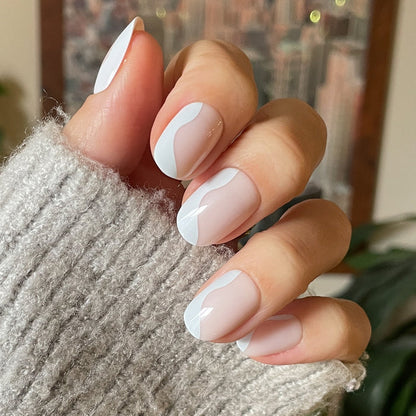 Side Swirl | Short | Round - Tab Press-On showing hand with neutral pink nails featuring a white pastel swirl design indoors