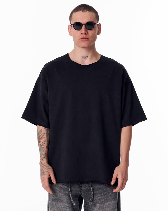 Martin Valen black oversized crew-neck T‑shirt, front close-up highlighting the raw-edge collar and relaxed oversized fit