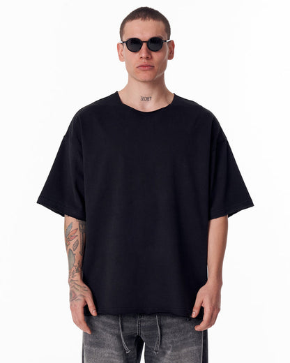 Martin Valen black oversized crew-neck T‑shirt, front close-up highlighting the raw-edge collar and relaxed oversized fit