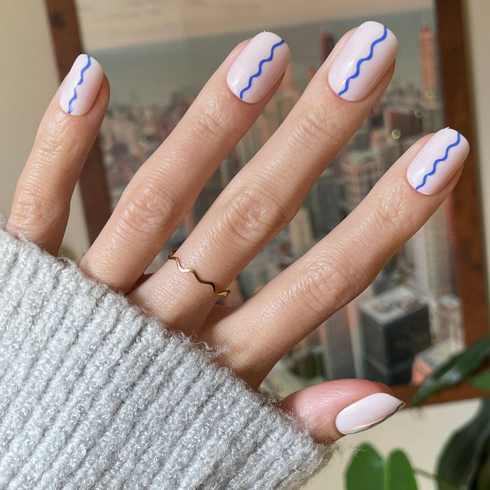 Simple Squiggle | Short | Squoval - Tab Press-On nails with neutral base and bright blue wavy line mani on hand indoors