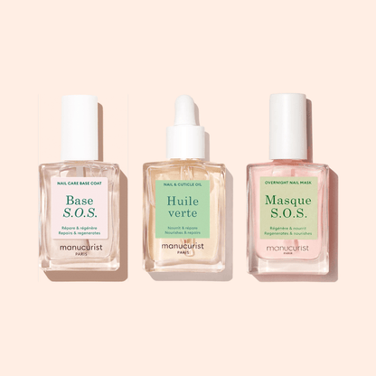 The Manucurist S.O.S Rescue Duo, displayed in clear glass bottles on a beige background, offers two targeted nail treatments—Base S.O.S. and Masque S.O.S.—designed to restore and strengthen damaged nails.