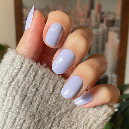 Sparkle Accent | Short | Round - Tab Press-On showing hand with light blue manicure and white sparkle details against cozy sweater background
