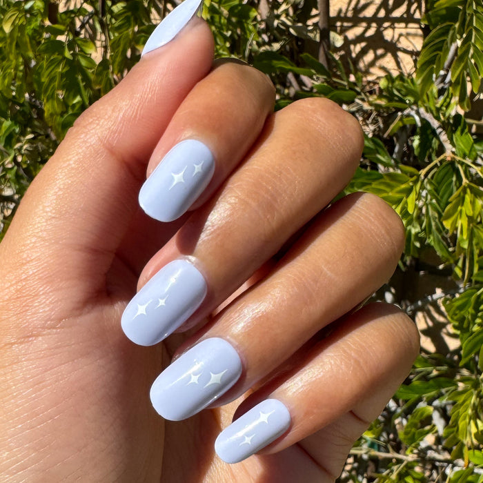 Sparkle Accent | Short | Round - Tab Press-On showing hand with light blue manicure and white sparkle details outdoors in sunlight