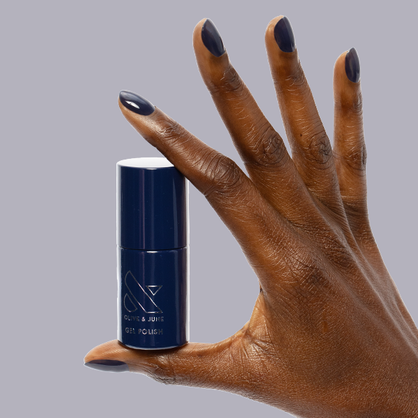 Suited - Gel dark navy gel polish bottle held by hand with matching glossy manicure by Olive and June