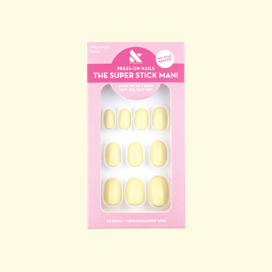 Sunny | Extra Short | Round - Tab Press-On nails in pastel yellow with non-damaging tabs in packaging on pale background