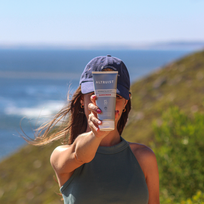 Person holding a Altruist sunscreen tube SPF30 with ocean view