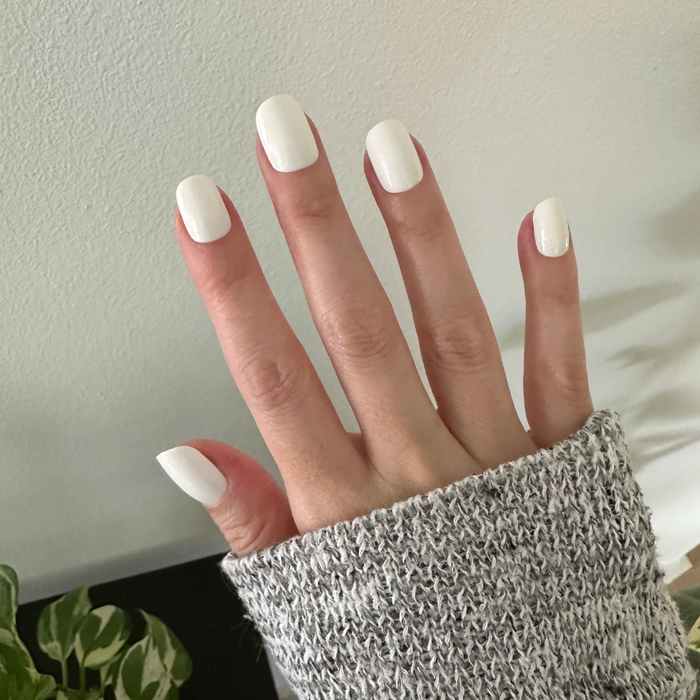 Swan | Extra Short | Squoval - Tab Press-On showing hand with crisp white press-on nails in cozy indoor setting