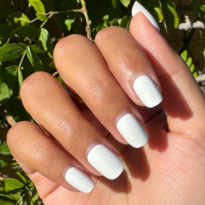 Swan | Extra Short | Squoval - Tab Press-On showing hand with bright white press-on nails outdoors in natural sunlight