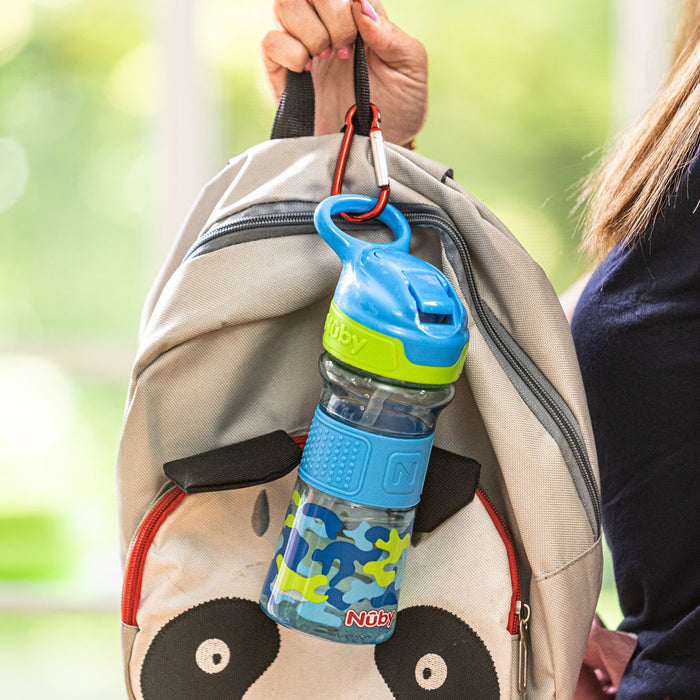 A person holds a gray backpack with a panda face; a Thirsty Kids REFLEX Easy Grip Water Bottle | Blue Camo is clipped to the bag with a red carabiner.