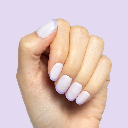 Tonal Lavender French | Extra Short | Round - Tab Press-On nails with soft lavender French tips on natural hand against lavender background