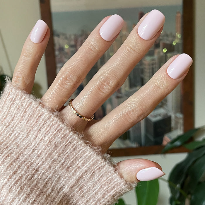 Tutu | Short | Squoval - Tab Press-On showing soft pastel pink false nails on hand with cozy sweater for easy at-home mani.