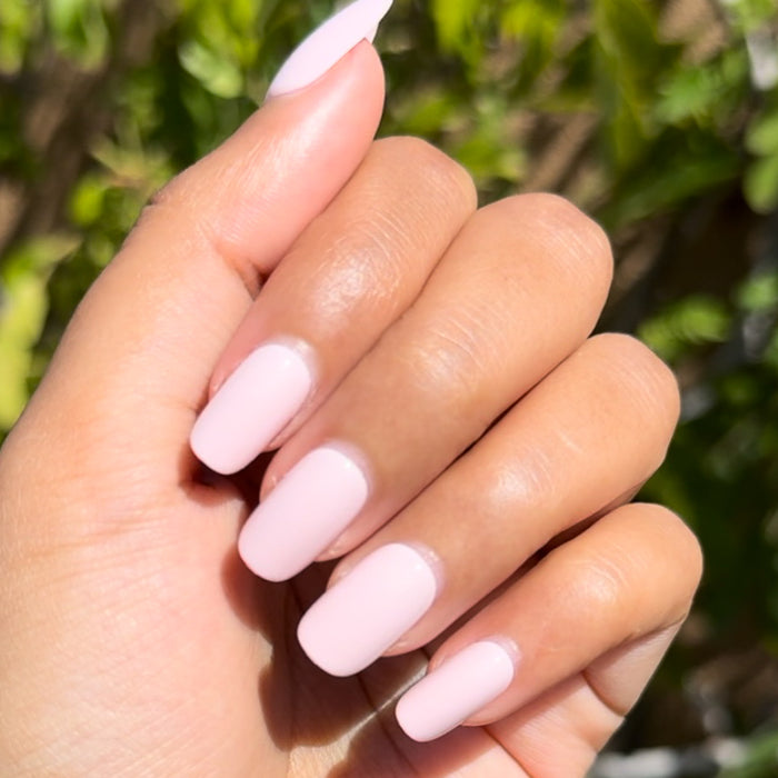 Tutu | Short | Squoval - Tab Press-On showing hand with pastel pink false nails outdoors in natural sunlight for easy mani.