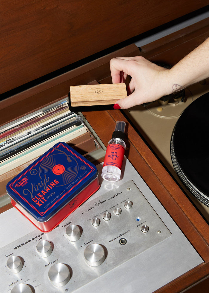 Vinyl cleaning kit components with velvet brush and fluid bottle on a turntable