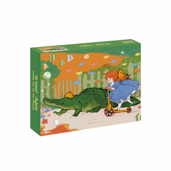 A girl in a blue dress rides a scooter alongside a large green alligator wearing a hat, with vibrant fish and plants in the background, featured on the box art of the WEVE Wani-Kun 500 Piece Jigsaw Puzzle—expertly crafted from premium blue board for a velvet-like soft touch.