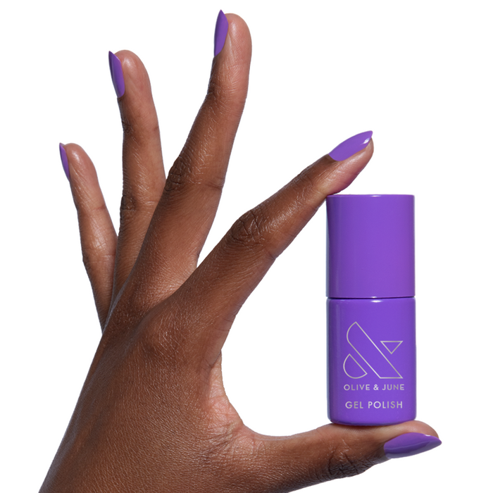 Wish You Were Here - Gel vibrant violet gel polish bottle held by hand with matching glossy manicure on natural nails
