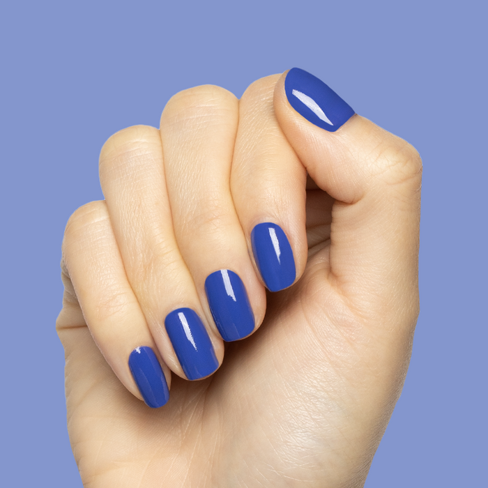 Hand with short rounded nails polished in bright denim blue Your Mani Looks So Good in Those Jeans - Gel manicure