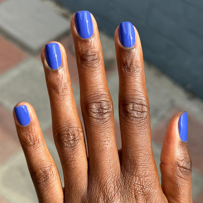 Hand with short nails painted bright denim blue Your Mani Looks So Good in Those Jeans - Gel polish manicure