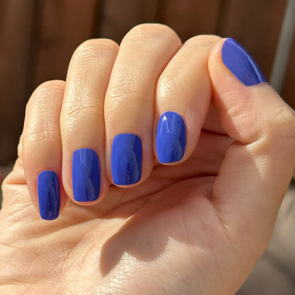 Hand with short nails painted bright blue Your Mani Looks So Good in Those Jeans - Gel manicure