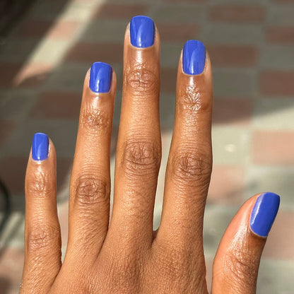 Hand with short nails painted bright denim blue Your Mani Looks So Good in Those Jeans - Gel manicure