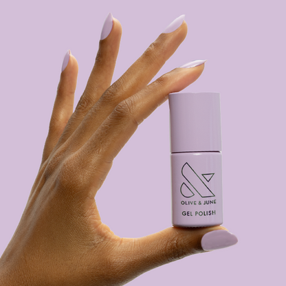 You're Invited - Gel bottle held by hand with matching soft lilac gel polish for a smooth manicure by Olive and June